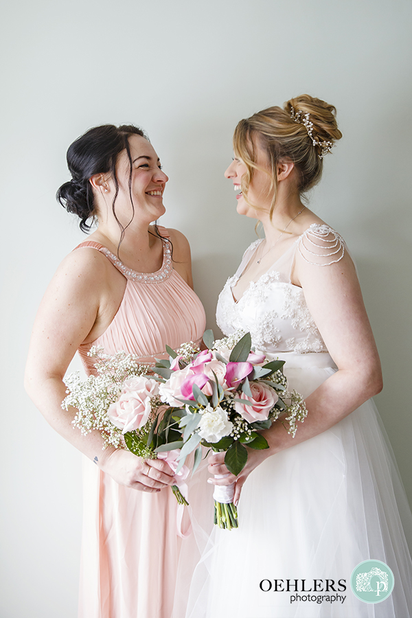 Bride with her Maid of Honour looking at each other and laughing