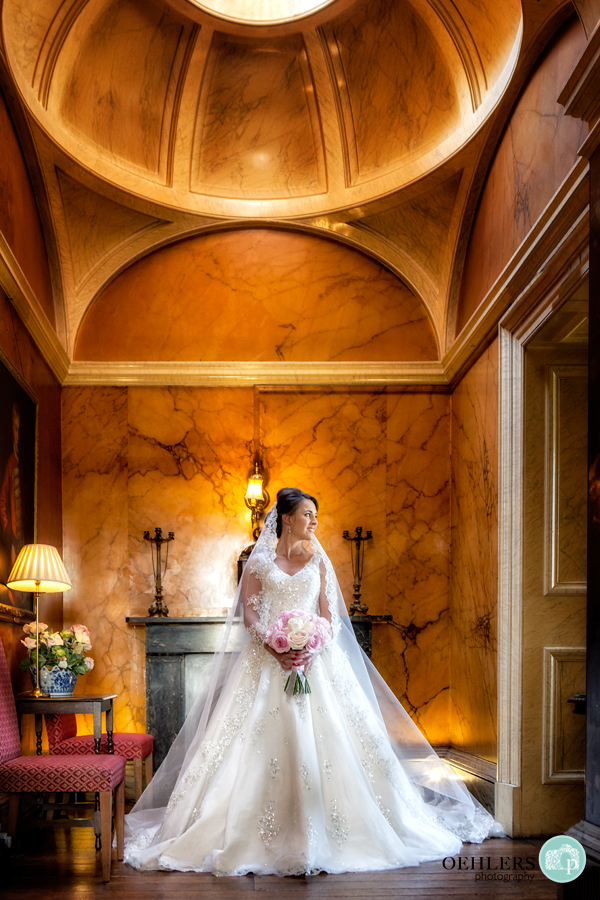 Bride in beautiful indoor surroundings looking to her left through a door