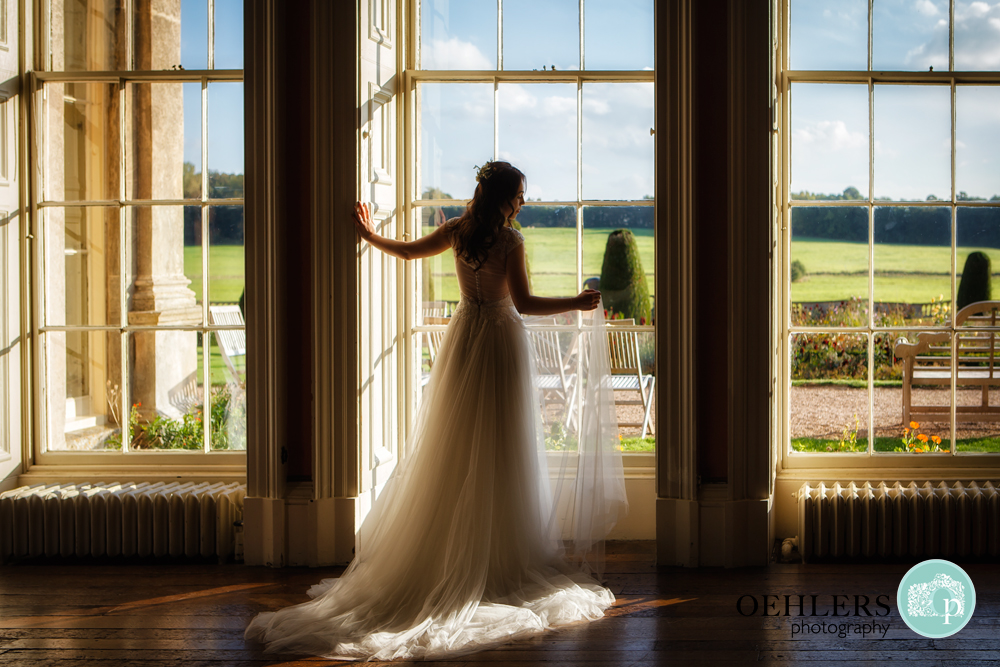 Silhouette of a bride posing against a floor to ceiling window.