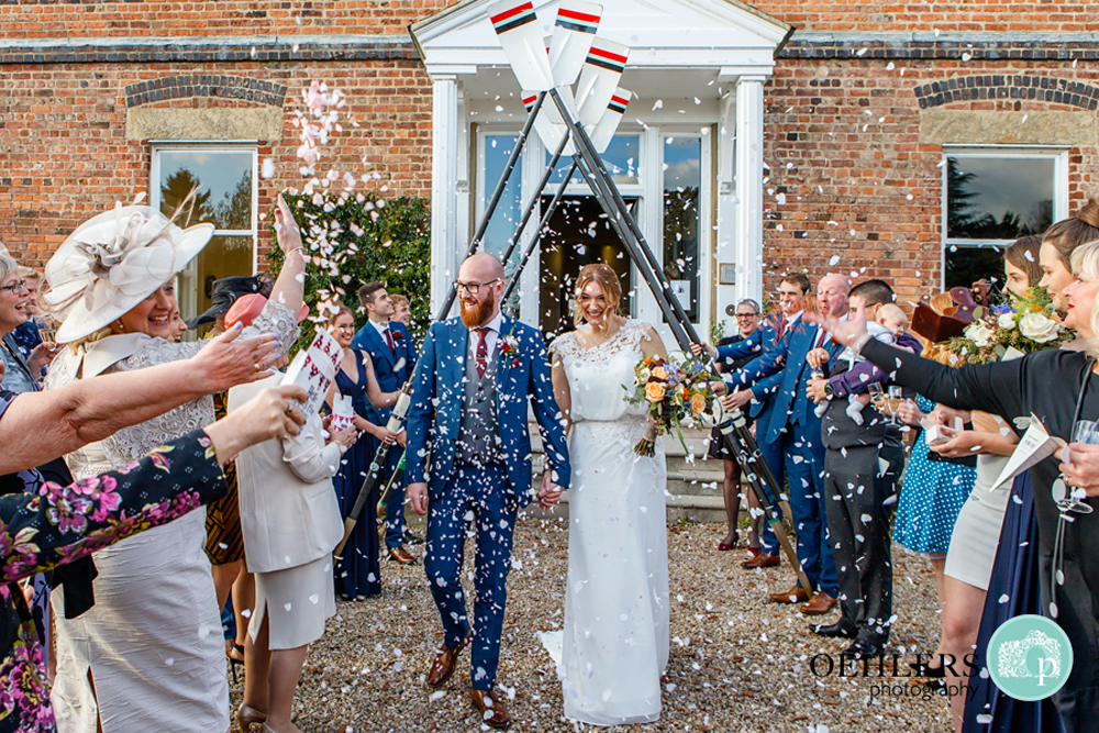 bride and groom walking through an arch of oars for their confetti shot
