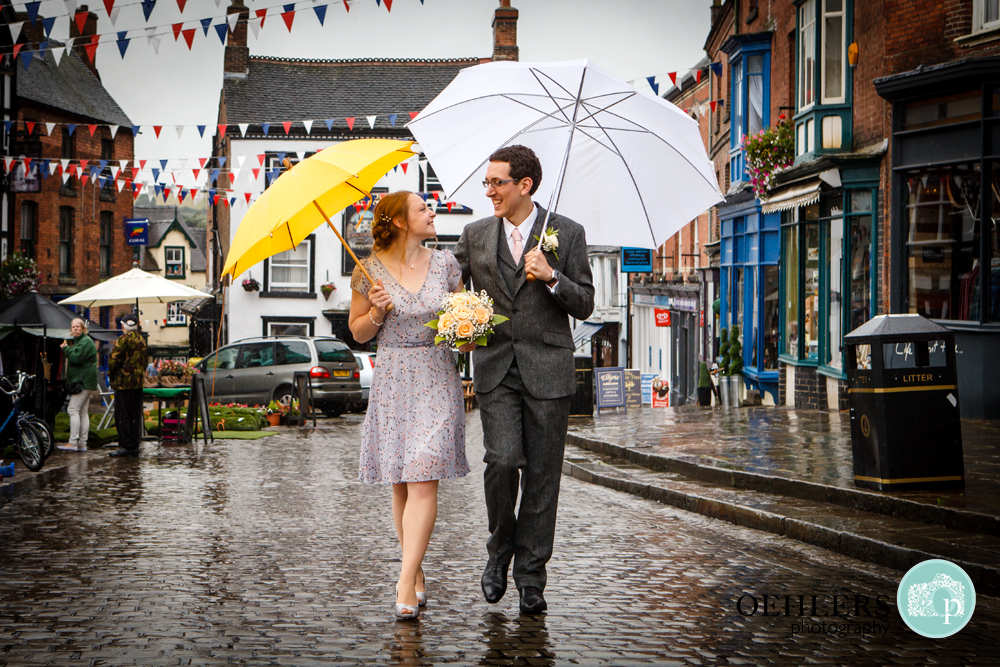 bride and groom walking with umbrellas in the rain