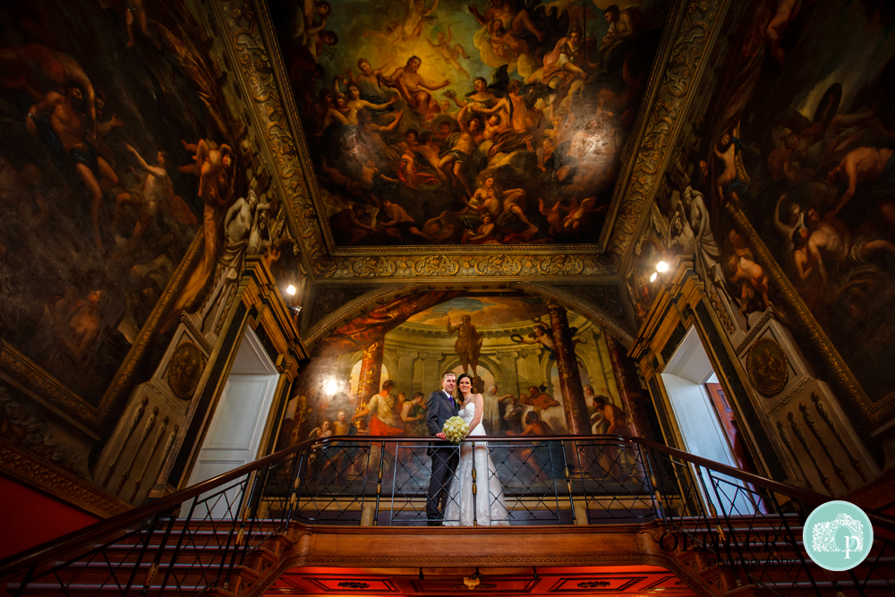 bride and groom standing on balcony with beautiful paintings as a backdrop