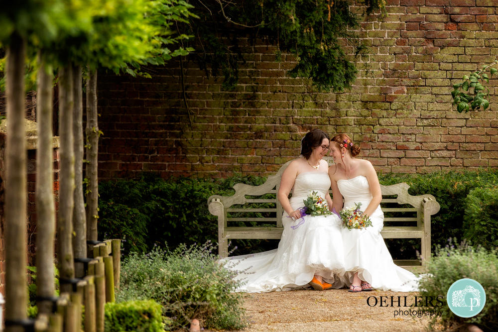 two brides sitting on a bench at the Walled Garden, Beeston