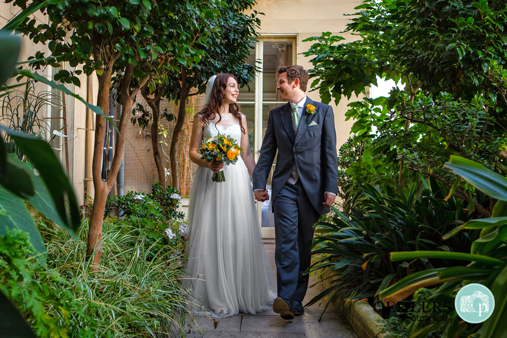 bride and groom walking in the conservatory at Prestwold