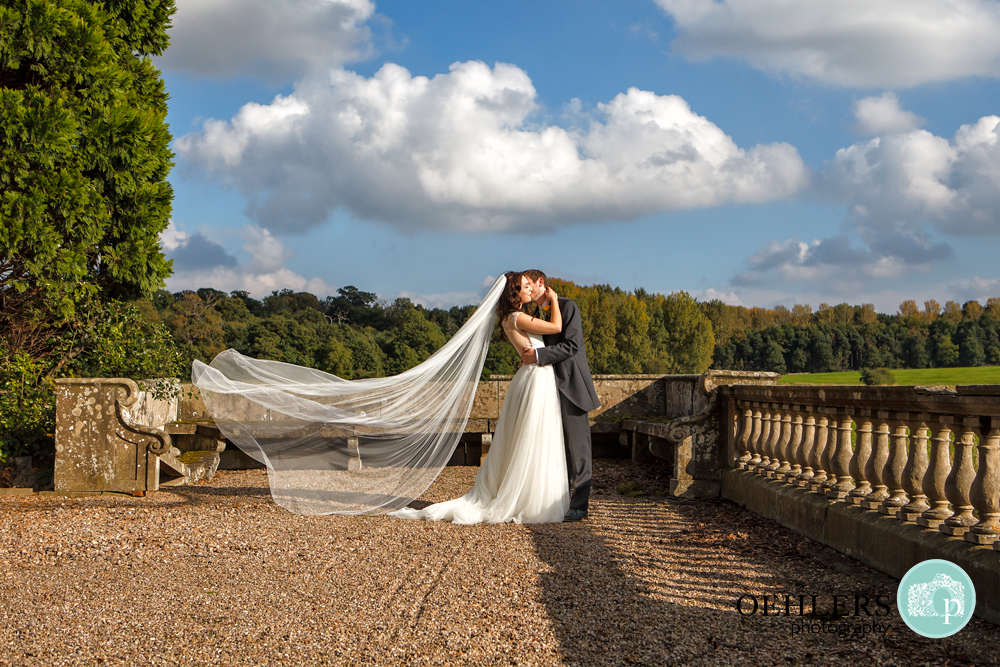 Veil flying behind bride as she kisses the groom