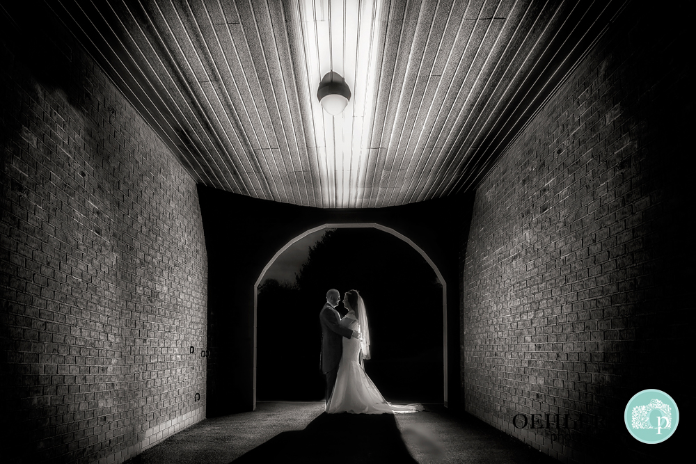 Black and White photo of Bride and Groom lit in an archway