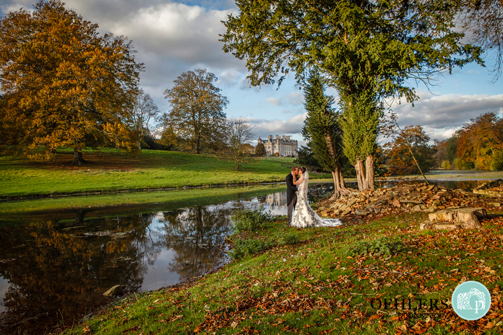 Bride and Groom by a lake with Stoke Rochford in the background