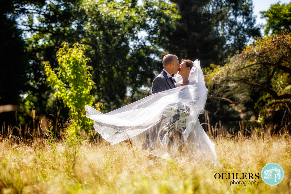 bride and groom kissing in a grassy field
