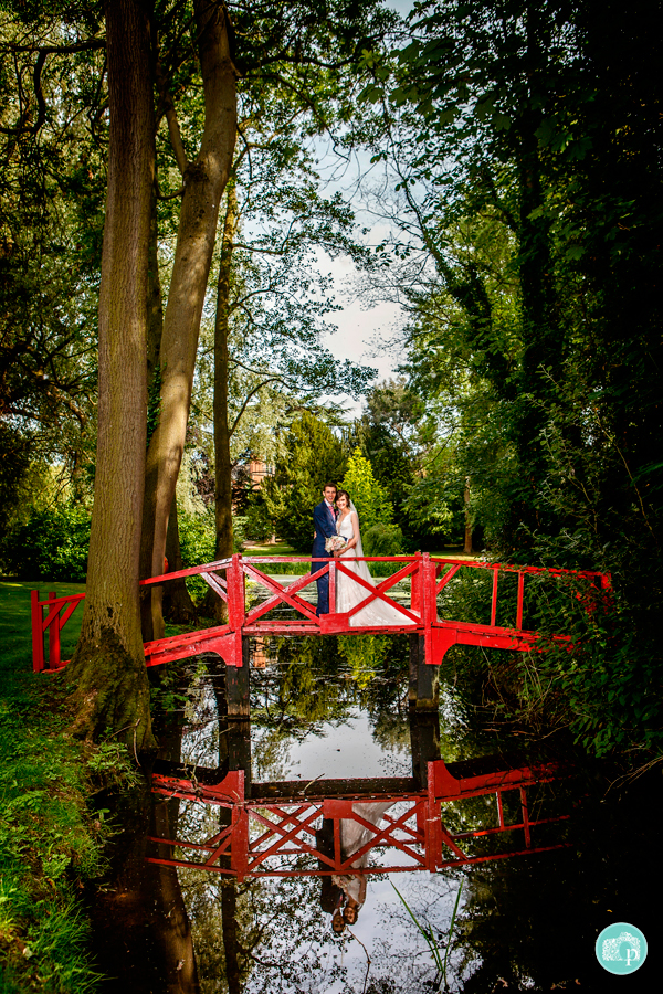 bride and groom posing on a red bridge