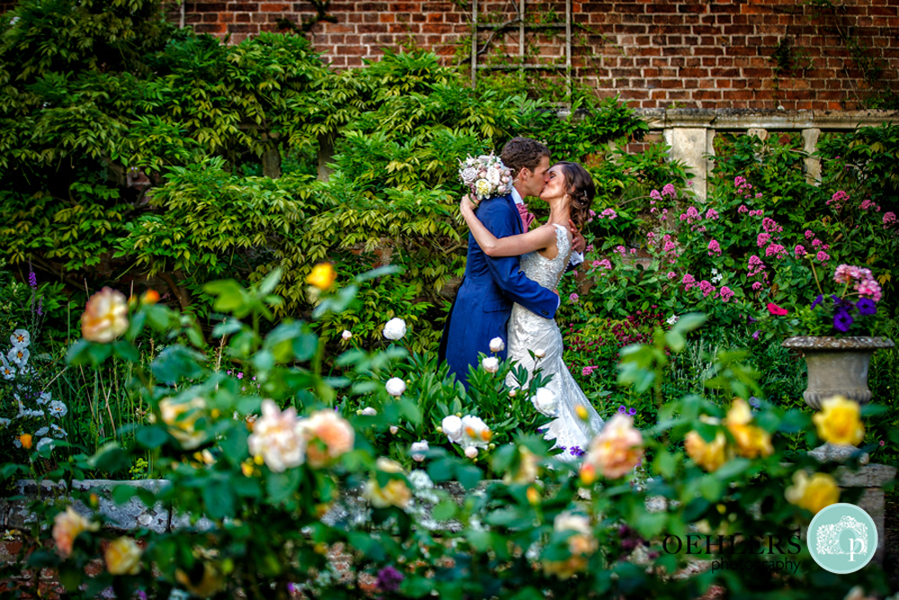 bride and groom kissing in the rose garden of Thrumpton Hall