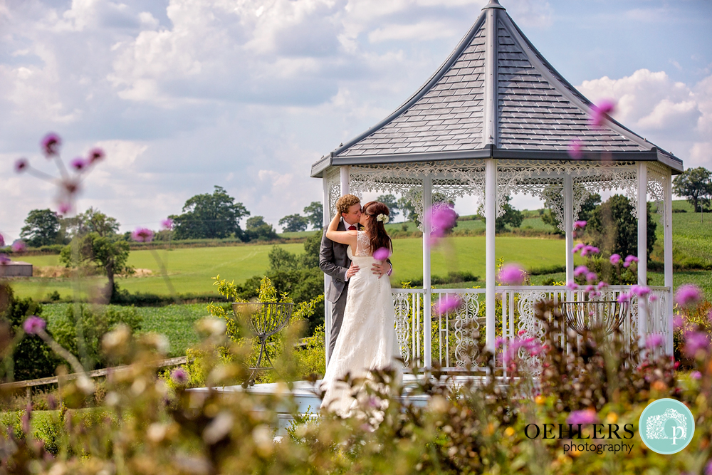 Bride and Groom kissing in the gazebo at Shottle Hall