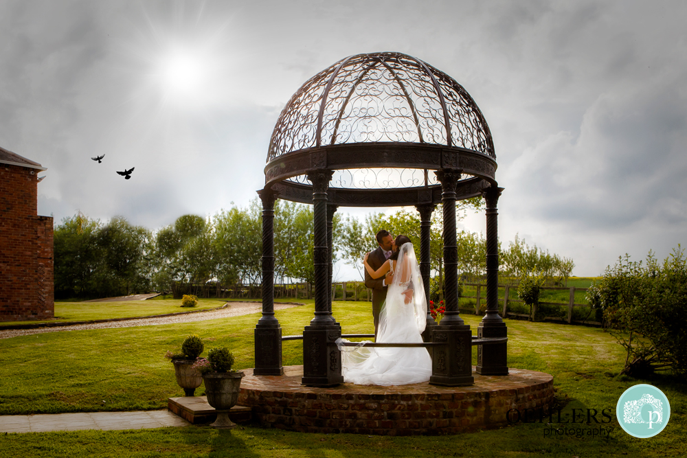 Bride and Groom kissing in the gazebo at Swancar Farm