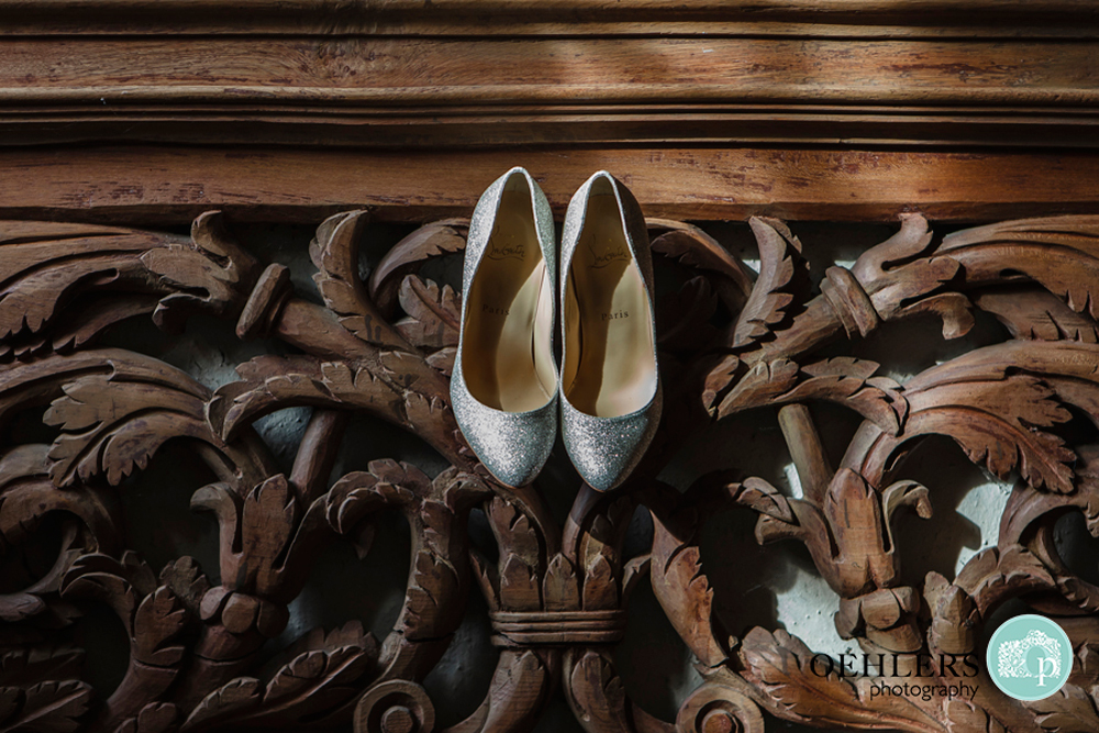 silver wedding shoes hanging from a wooden carved staircase