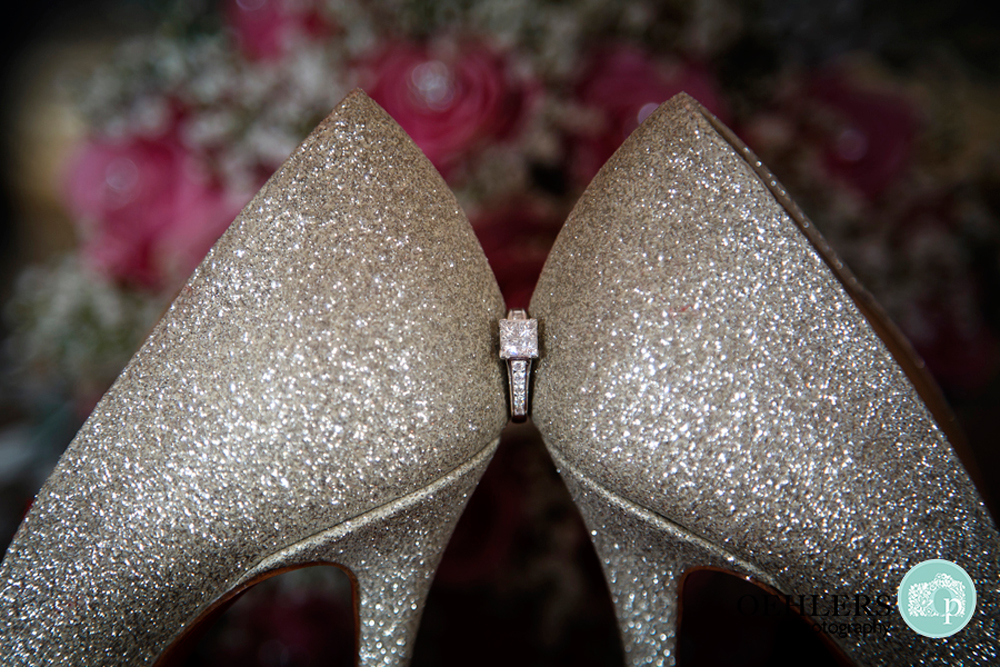 engagement ring in between backs of shoes
