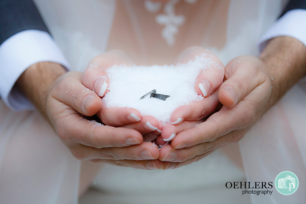 rings on snow held in groom's and bride's hands