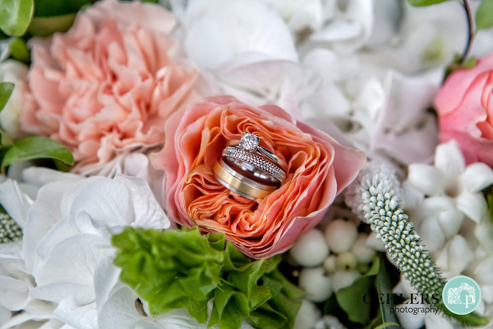 wedding rings and engagement ring balancing in a flower