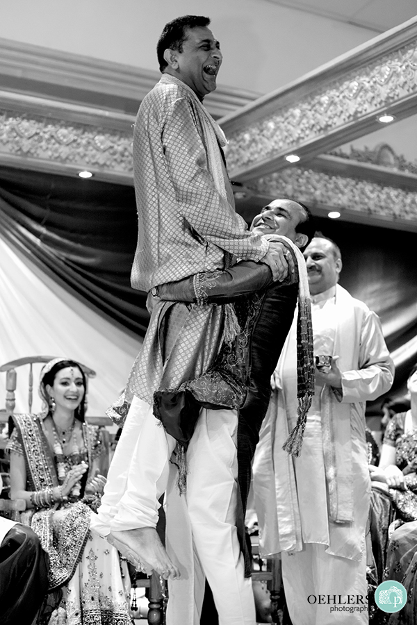 Indian wedding guests lifting father of the bride up