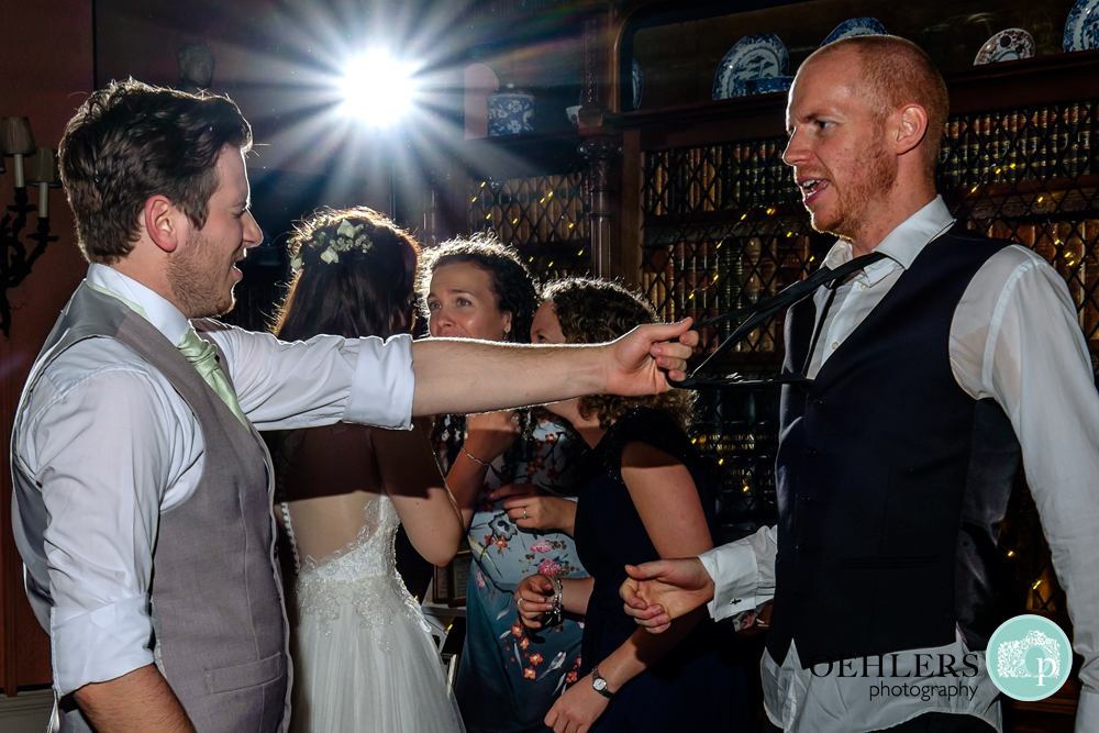 Groom pulling a guests tie whilst enjoying the party