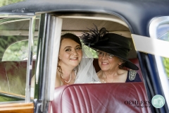 bride looking out of car with mum at her side