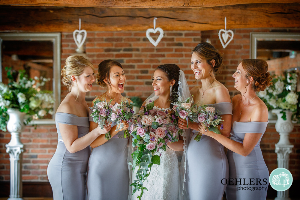 Brides laughing and looking at bride in a group photograph