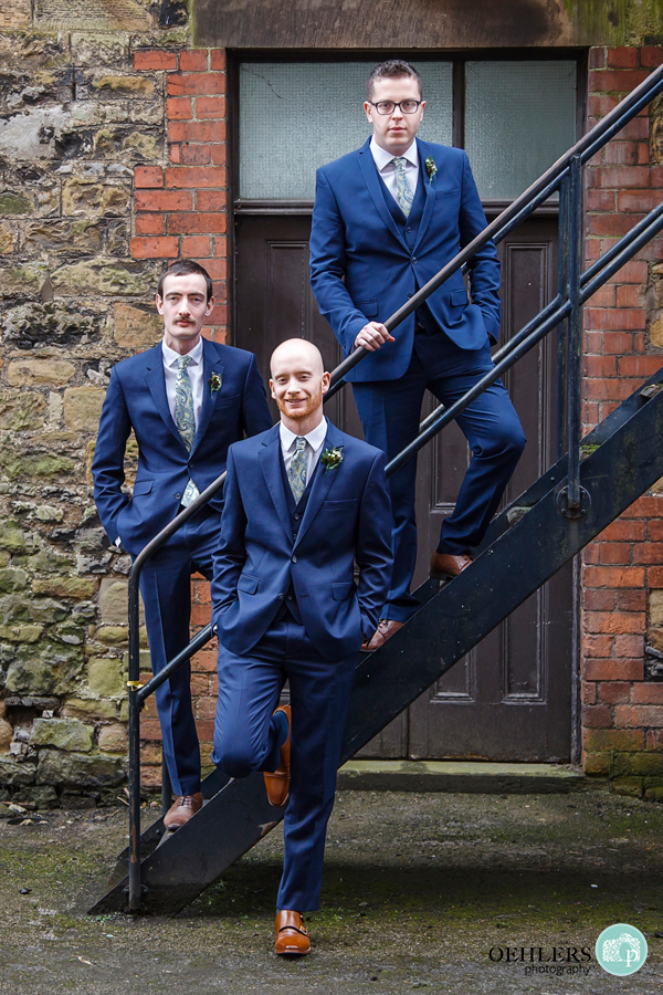 Groom posing with bestmen on metal staircase outside