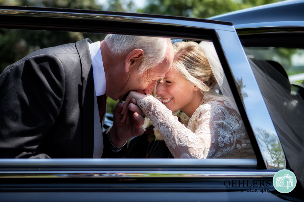 dad kissing hand of bride whilst getting her out of car
