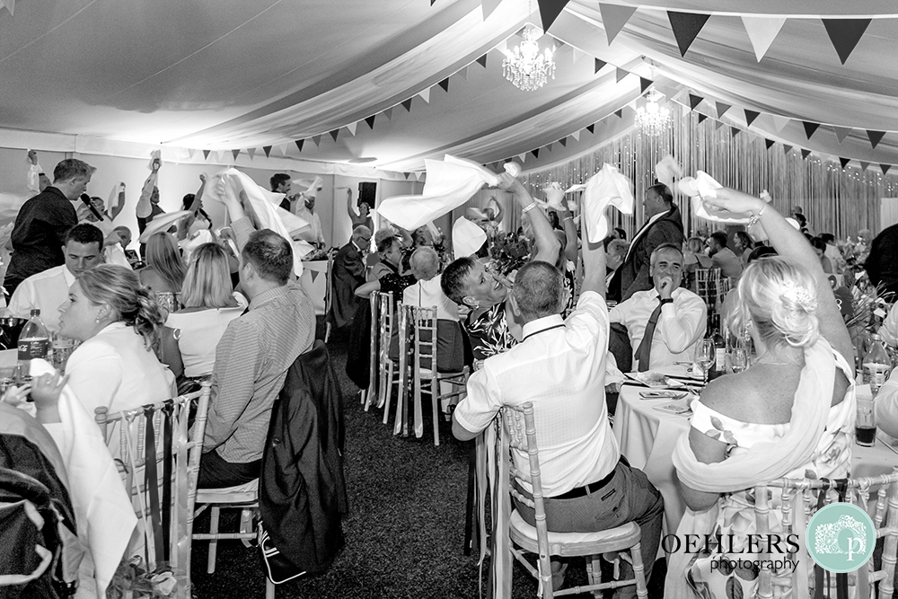 Guests waving their serviettes whilst the singing waiters perform