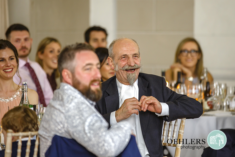 Uncle with moustache and pointed beard laughing at a speech