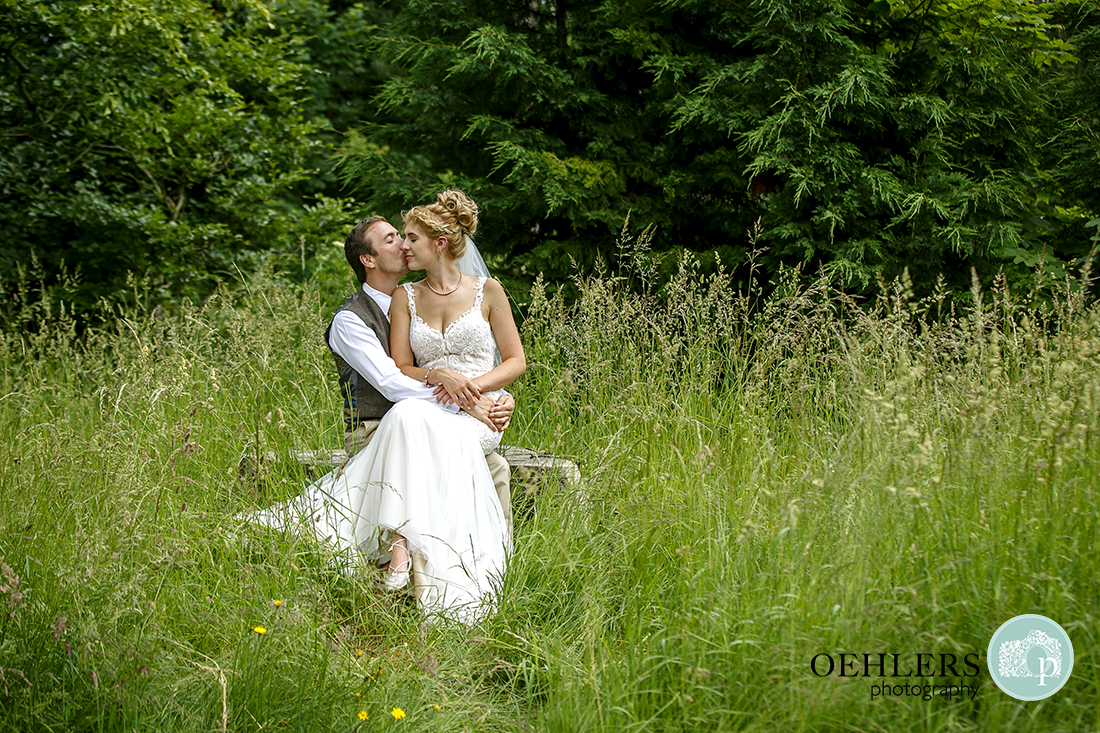 Bride sitting on Groom's lap in the grass