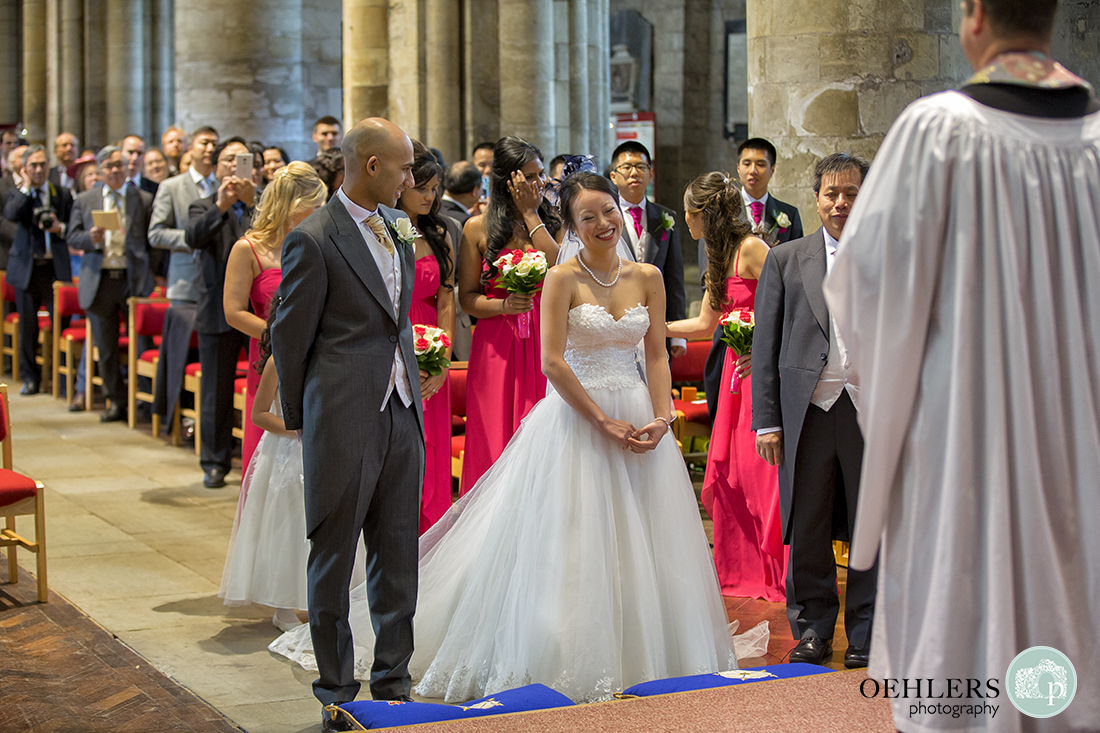 Happy bride arrives at the altar in Selby Abbey with the Groom smiling at her.