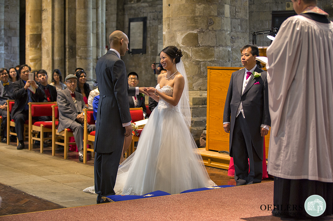 Bride slipping on the wedding ring for her Groom.