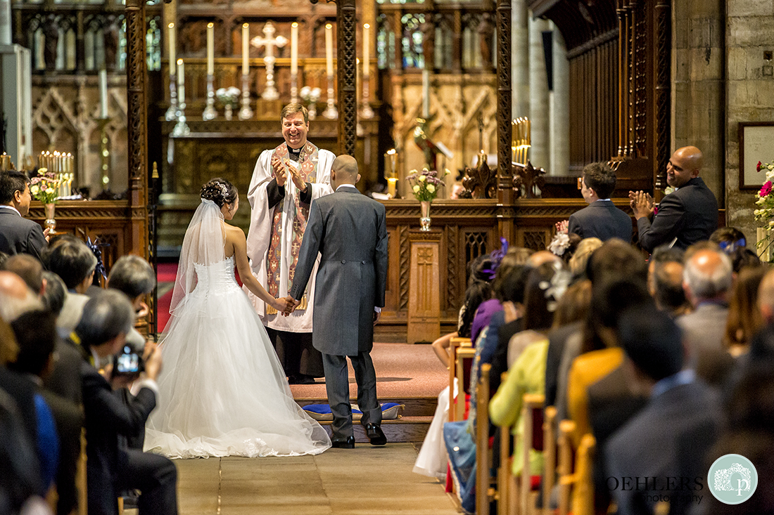 Photograph taken from the back of the congregation applauding the Bride and Groom.