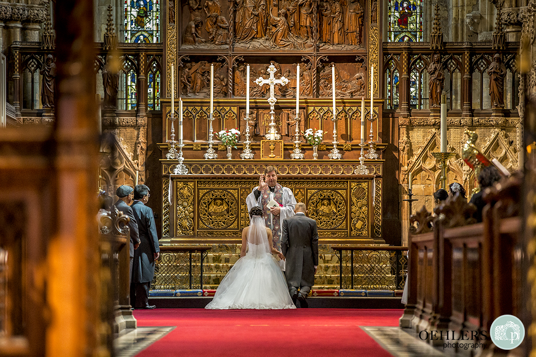 Bride and Groom kneeling at the intricately carved altar having their blessing.