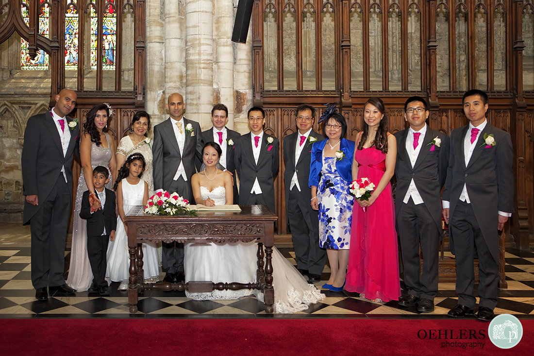 Formal group photograph of the bride and groom at the registry table with the family members.