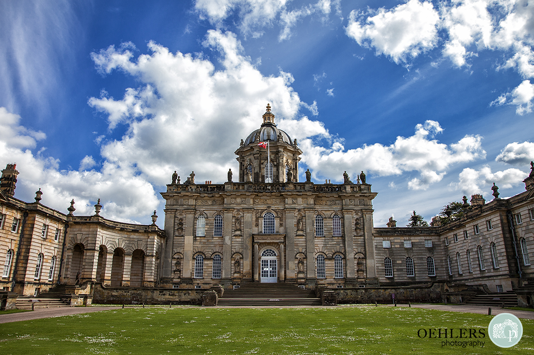 Fascade of Castle Howard Wedding Venue on a sunny day with blue skies and fluffy clouds.