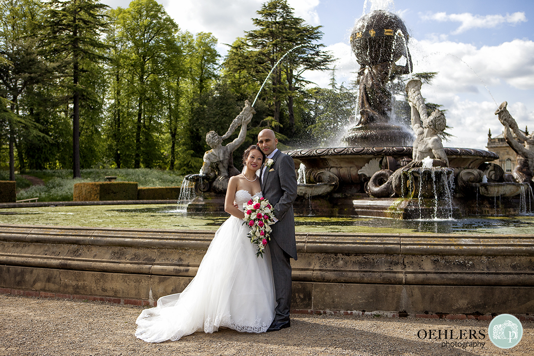 Formal photo of Bride and Groom posing in front of the Atlas Fountain at Castle Howard.