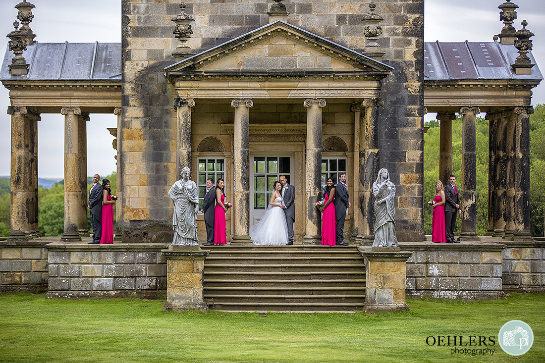 Bridal Party posing for a photograph at The Temple of the Four Winds back to back and alternating from groomsman to bridesmaid.