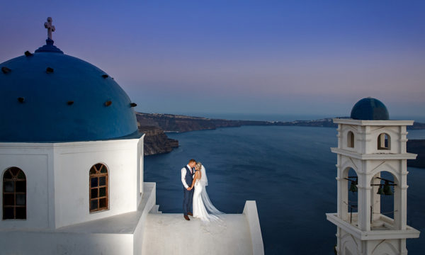 Nottingham Wedding Photographers-Bride and Groom on top of a church building overlooking the caldera in Santorini.