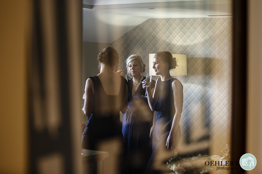 Reflection of bridesmaids in their satin dresses drinking champagne.