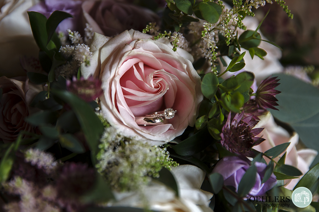 Shustoke Barn Wedding Photographers-Close-up photograph of the wedding rings in a beautiful, delicate blush-pink rose on the bride's bouquet.