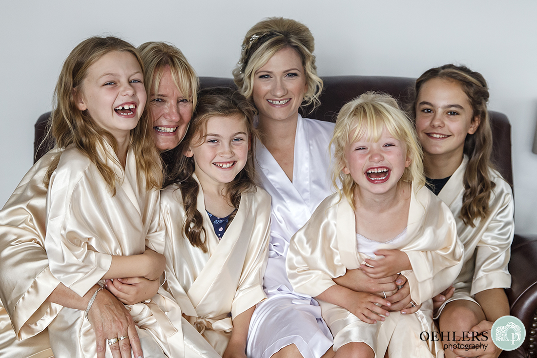 portrait of the bride sitting on a sofa with her flower girls, bridesmaid and mum