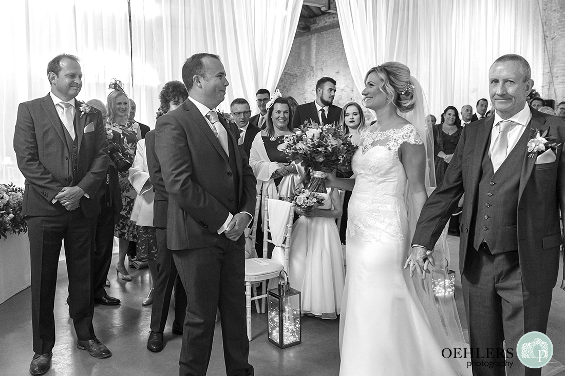 bride smiling at her groom after walking down the aisle with her dad