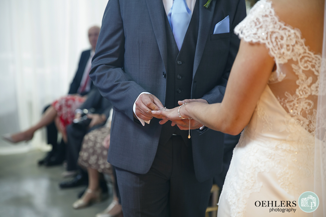 grrom gently putting the wedding ring on the bride's finger