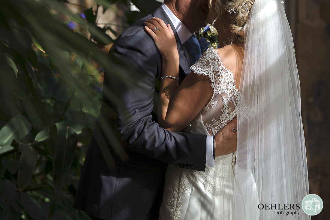 close up of couple's torsos as they hug and kiss showing the detail on the bride's dress