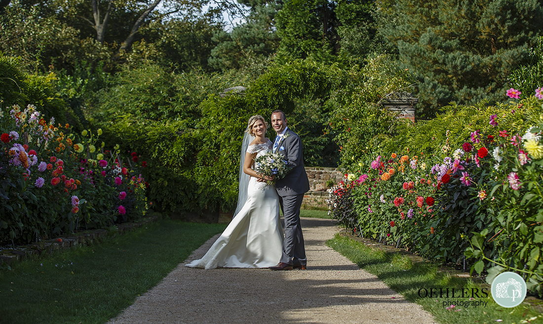 couple portrait in the middle of a pathway bordered by colourful flowers