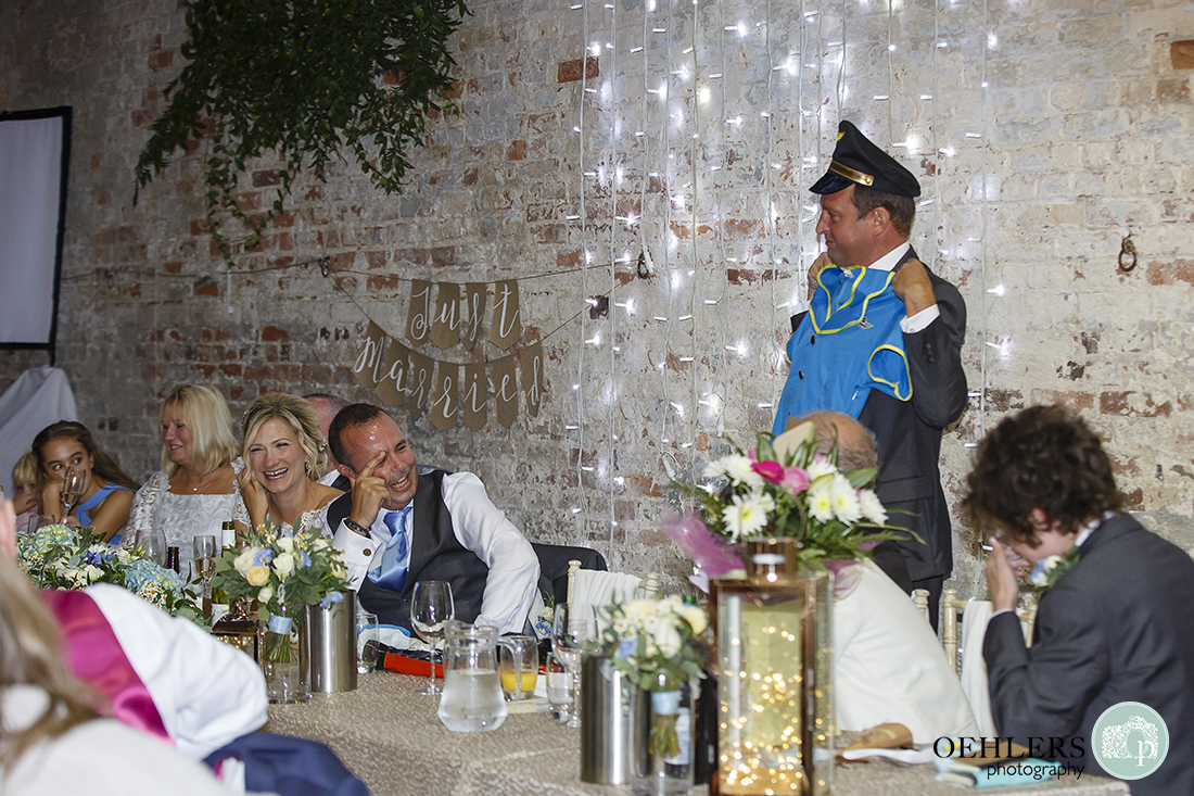 bestman shows the guests, during his speech, the air hostess outfit the groom wore on his stag do