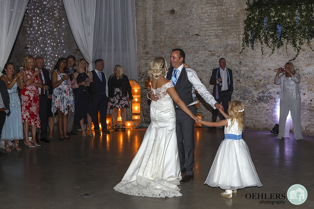 guests gather to watch the first dance with the couples' young daughter holding their hands