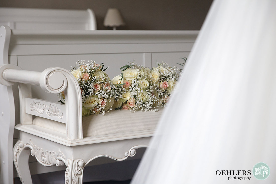 Wedding bouquets on the bench in front of wedding dress