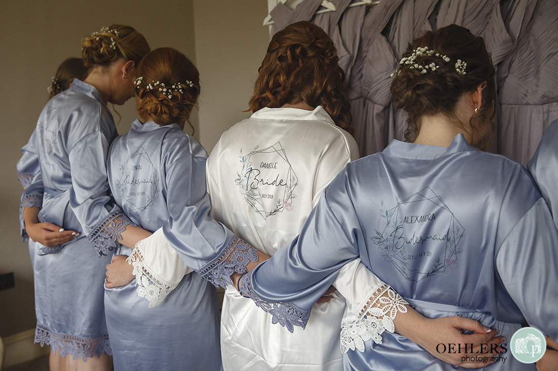 Bride and bridesmaids with backs to camera to show off their names on their dressing gowns