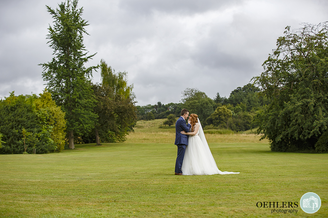 Photograph shows off the beautiful landscape surrounding Thrumpton Hall with Bride and Groom in the middle.